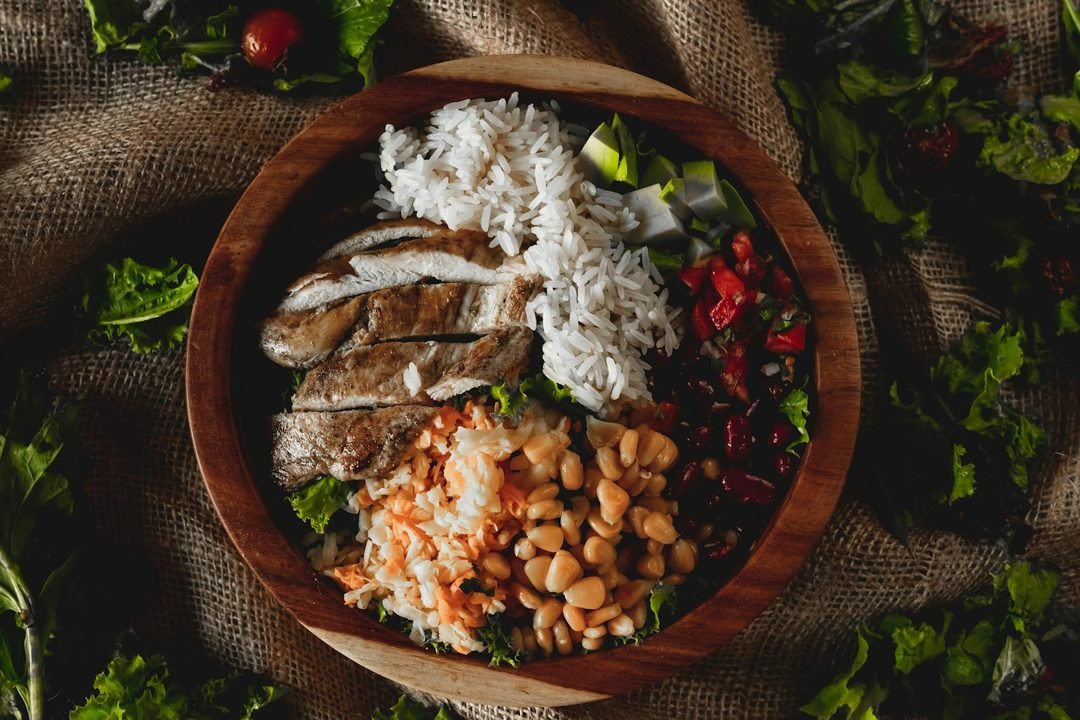 Bol repas riche en protéines : poulet grillé, riz, pois chiches et haricots rouges